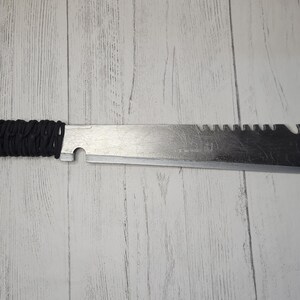 Peut inclure: Une machette argent&eacute;e avec une poign&eacute;e en paracorde noire. La lame est dentel&eacute;e et comporte un trou pr&egrave;s de la pointe.