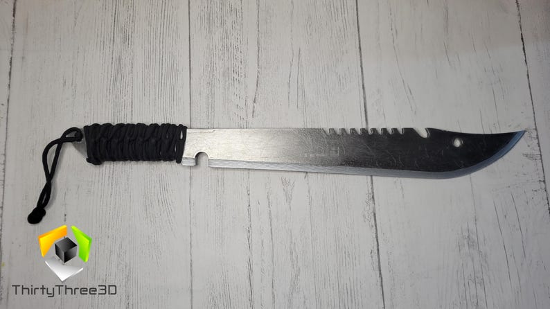 Peut inclure: Une machette argent&eacute;e avec une poign&eacute;e en paracorde noire. La lame est dentel&eacute;e et comporte un trou pr&egrave;s de la pointe.