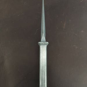 May include: A silver dagger with a pointed tip and a decorative handle. The handle has a series of small, round indentations.