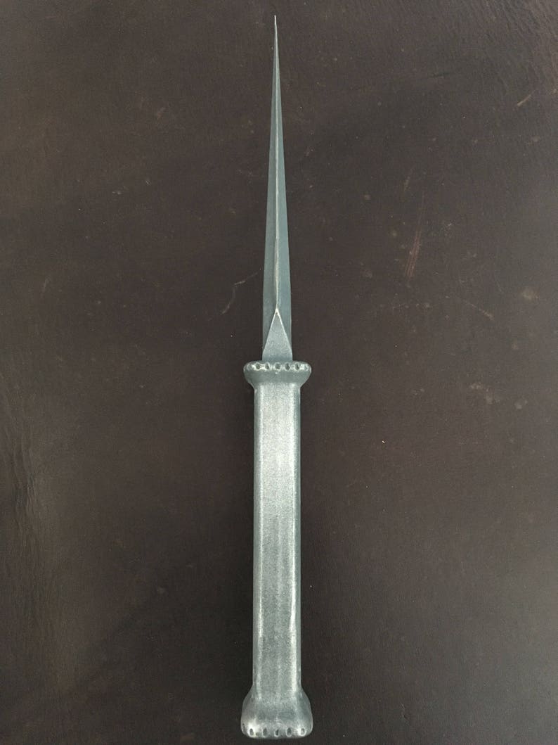 May include: A silver dagger with a pointed tip and a decorative handle. The handle has a series of small, round indentations.