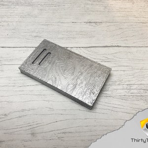 May include: A silver metal phone case with a wood grain pattern. The case has three slots for cards.