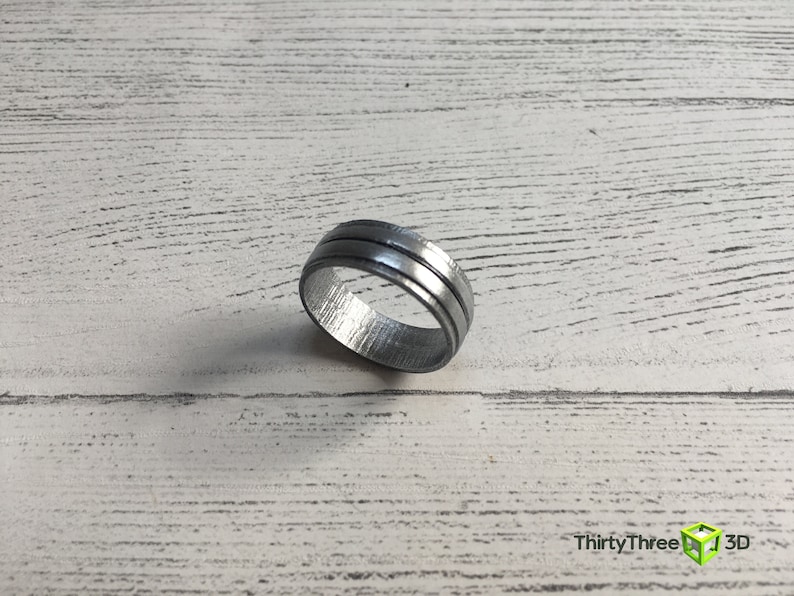 May include: A silver ring with two grooves around the band.