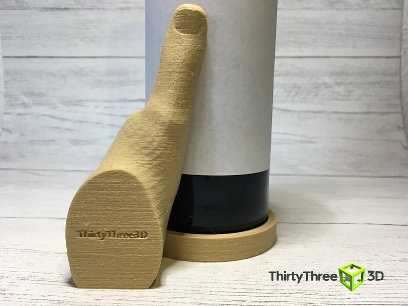 May include: A 3D printed wooden hand holding a wine bottle. The hand is giving a thumbs up and has the text "ThirtyThree3D" printed on the palm. The bottle is sitting on a wooden coaster.