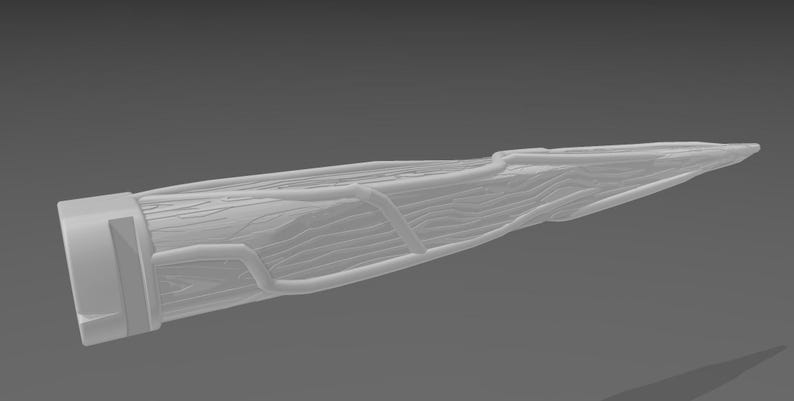 May include: A light gray, elongated object with a textured, wood-like appearance. The design features a rectangular base and a pointed tip. The surface has visible grain and raised, curved lines, suggesting a natural, organic form. The object is set against a gray background.