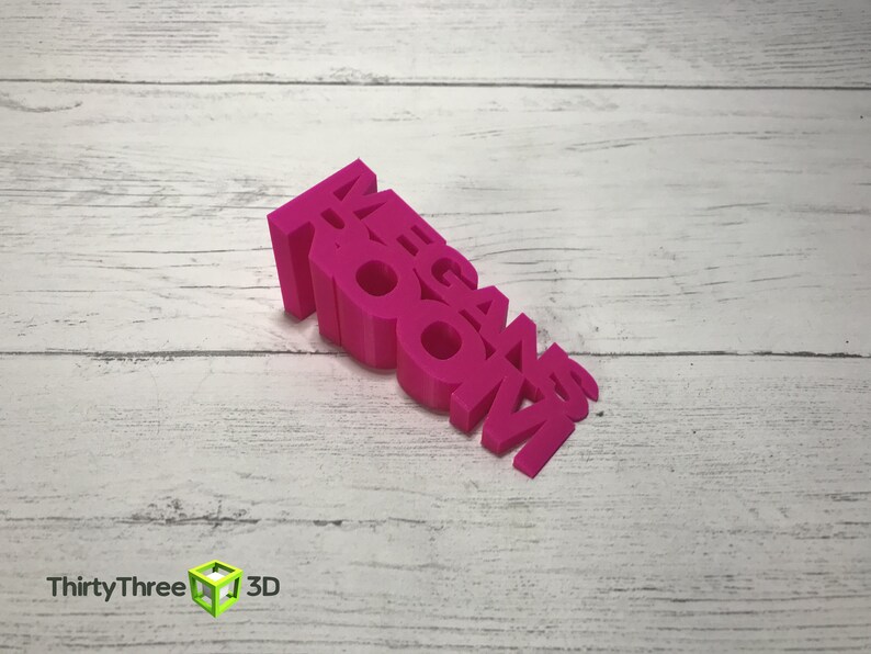 May include: A pink 3D printed word block that reads "MEGAN ROOM".