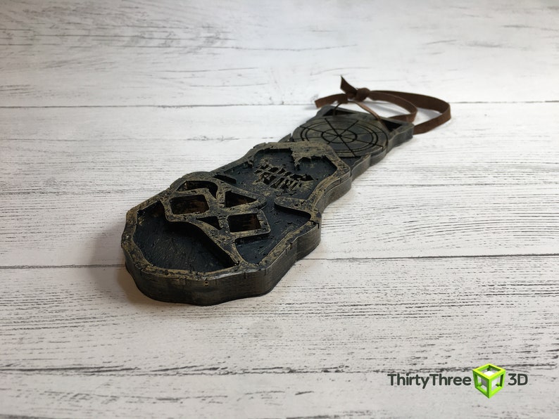 May include: A dark brown wooden key with a skull and crossbones design. The key has a loop at the top for hanging.