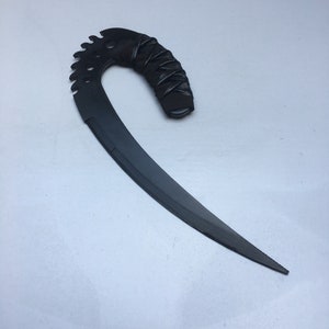 May include: A black, curved, metal knife with a serrated edge and a leather-wrapped handle.