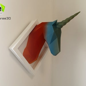 May include: A 3D printed unicorn head sculpture in a white frame. The unicorn is painted in shades of blue, green, and orange.