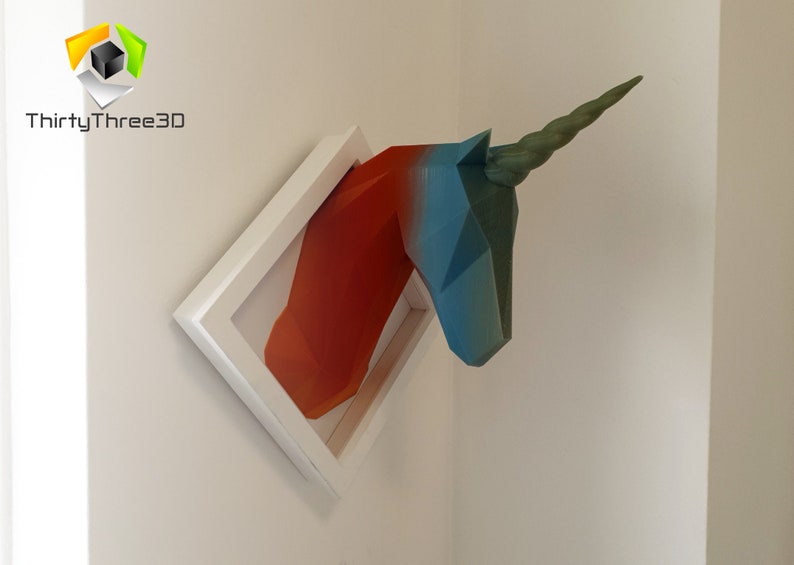 May include: A 3D printed unicorn head sculpture in a white frame. The unicorn is painted in shades of blue, green, and orange.