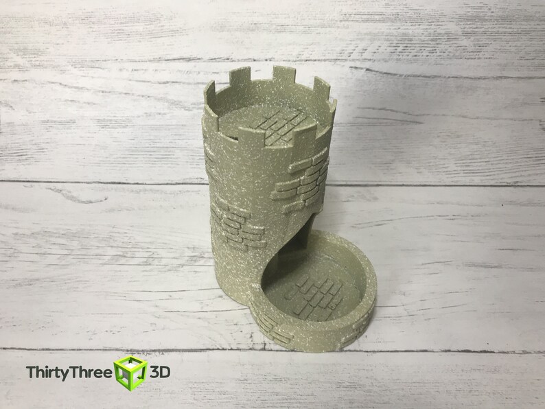 May include: A beige, 3D printed tower-shaped dice rolling tray with a textured brick pattern. The tower has a crenellated top and a curved opening for dice to roll out.