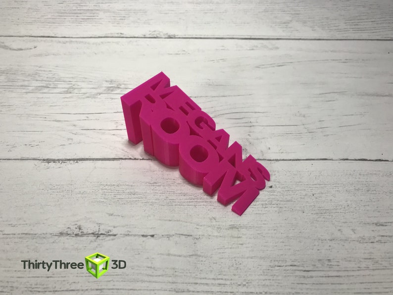 May include: A pink 3D printed word block that reads "MEGAN ROOM".