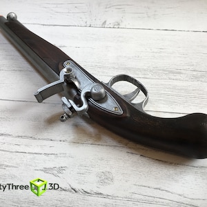 Puede incluir: R&eacute;plica de pistola de chispa con culata de madera marr&oacute;n oscuro y mecanismo de metal plateado. El ca&ntilde;&oacute;n tambi&eacute;n es plateado y la punta es naranja. La pistola es un accesorio o un art&iacute;culo decorativo.