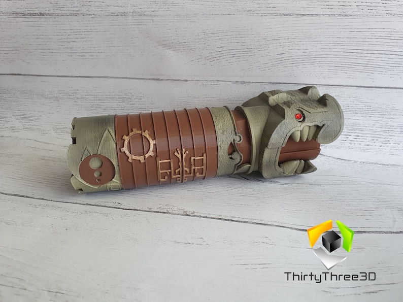 May include: A 3D printed, brown and gray, steampunk-style, dragon head pipe. The dragon has a red eye and sharp teeth. The pipe is decorated with gears and other intricate details.