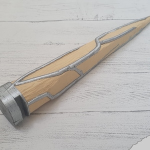 Op de afbeelding: Een zilveren en beige 3D-geprint rekwisietwapen met een puntige punt en een getextureerd oppervlak.