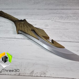 May include: A silver and gold-colored fantasy-style dagger with a curved blade and intricate details. The dagger is made of a durable material and has a sharp point.