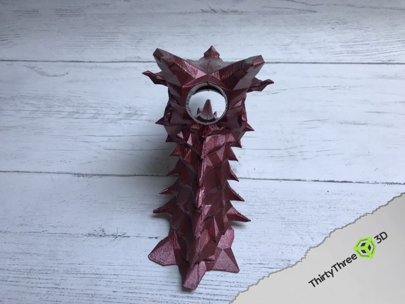 May include: A 3D printed, burgundy-colored, dragon-shaped object with a white, circular opening in the center of its head.