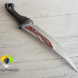May include: A silver dagger with a black handle and red accents. The blade has a decorative design with a sharp point.