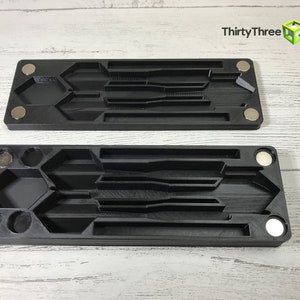 Pode incluir: Duas bandejas de pl&aacute;stico preto com m&uacute;ltiplos compartimentos para guardar ferramentas ou outros objetos pequenos. As bandejas t&ecirc;m &iacute;m&atilde;s nas laterais e s&atilde;o projetadas para serem empilhadas.