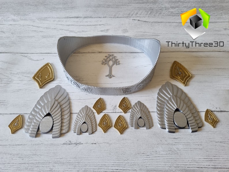 May include: A silver crown with a tree design, along with several silver and gold pieces, including a set of three arches.