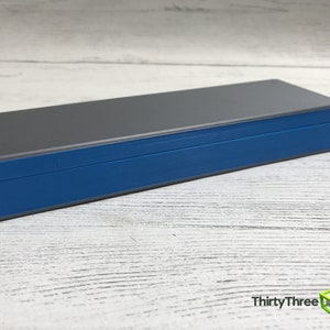 May include: A gray and blue rectangular box with a lid. The box is made of plastic and has a smooth surface.