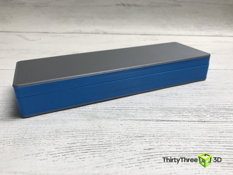 May include: A gray and blue rectangular box with a lid. The box is made of plastic and has a smooth surface.
