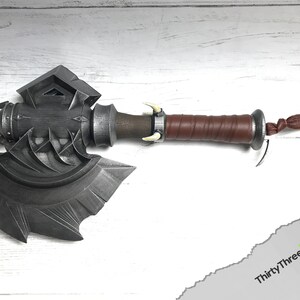 May include: A silver axe with a brown leather handle and a silver skull-like design on the head. The axe has a decorative knot at the end of the handle.