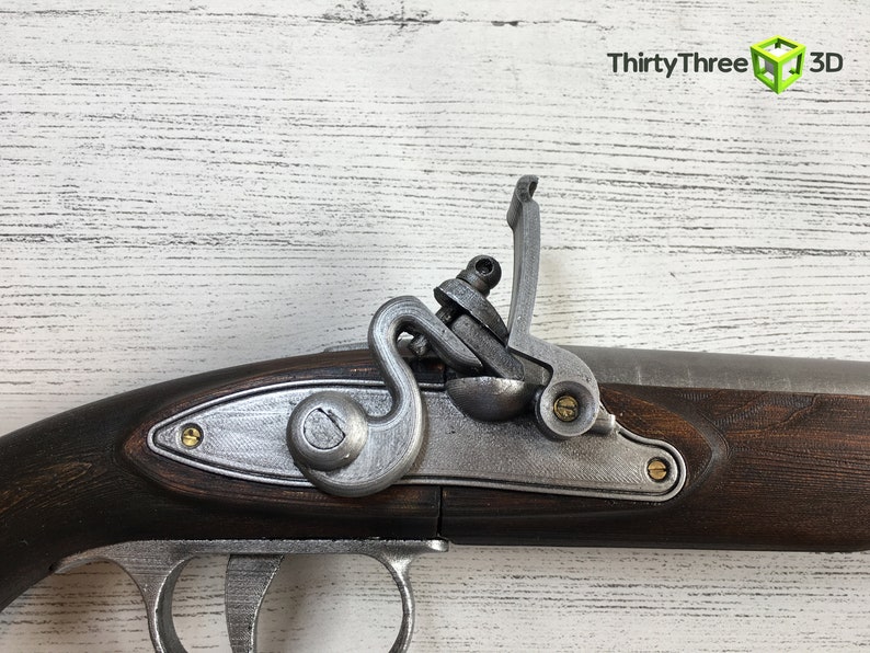 Puede incluir: Primer plano de una r&eacute;plica de pistola de chispa. La pistola presenta una culata de madera marr&oacute;n oscuro, componentes met&aacute;licos plateados y detalles de lat&oacute;n. La imagen incluye el texto "ThirtyThree 3D".