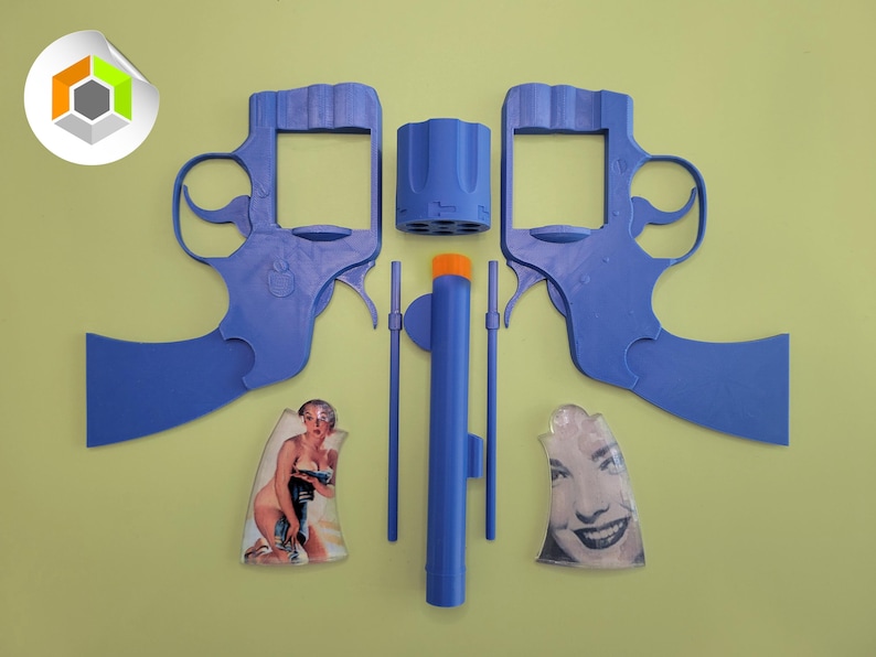 Op de afbeelding: Een gedemonteerde blauwe speelgoedrevolver met een oranje punt, met twee framehelften, een cilinder en andere componenten. De afbeelding bevat ook twee vintage pin-up afbeeldingen.