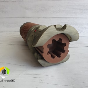 May include: A 3D printed model of a lightsaber hilt with a brown and gray color scheme. The hilt is open, revealing a brown gear inside.