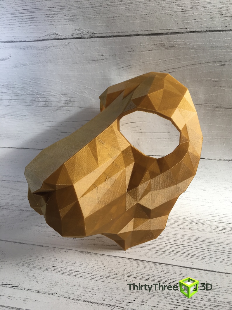 May include: A gold-colored, 3D printed mask with a geometric design. The mask has a single eye hole and is made of a textured material.