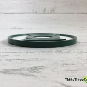 Puede incluir: Posavasos redondo de color verde oscuro con el logotipo de Linterna Verde.