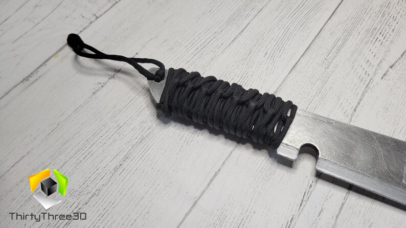 Peut inclure: Un couteau &agrave; lame argent&eacute;e envelopp&eacute; de paracorde noir avec un ouvre-bouteille. Le couteau est dot&eacute; d'un cordon noir attach&eacute; &agrave; la poign&eacute;e.
