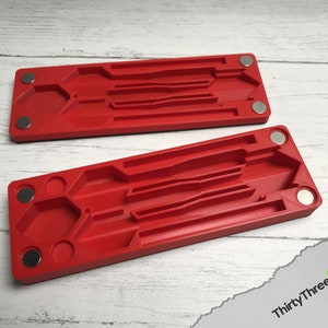 Pode incluir: Duas bandejas de pl&aacute;stico vermelho com &iacute;m&atilde;s nas laterais. Cada bandeja tem v&aacute;rias ranhuras e um recorte hexagonal.