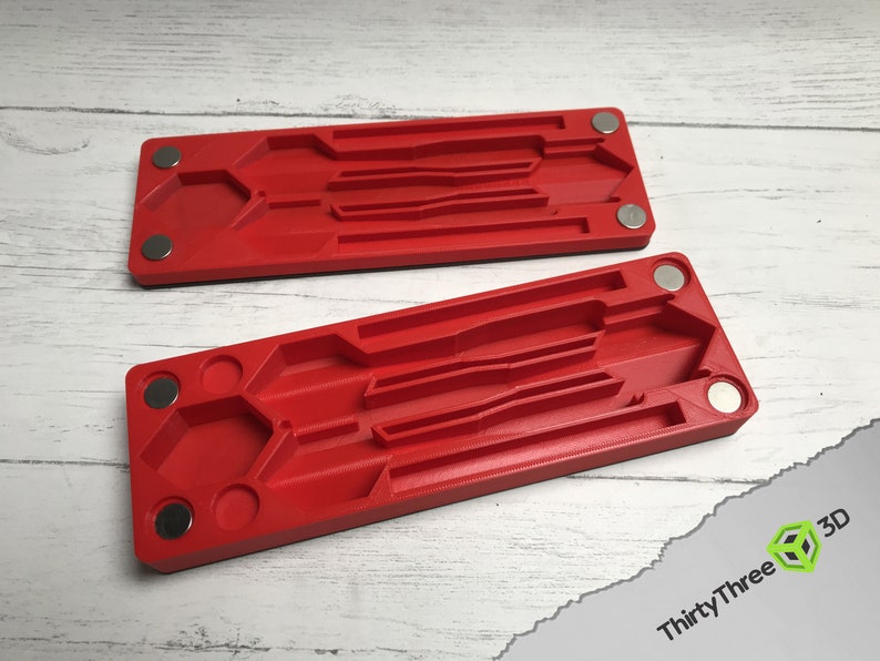 Pode incluir: Duas bandejas de pl&aacute;stico vermelho com &iacute;m&atilde;s nas laterais. Cada bandeja tem v&aacute;rias ranhuras e um recorte hexagonal.