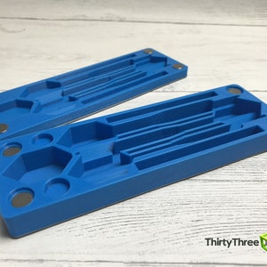 May include: Two blue plastic storage boxes with multiple compartments and magnets on the sides. The boxes are designed to hold small items like tools or jewelry.