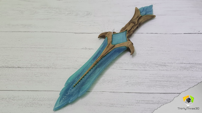 May include: A blue and gold fantasy-style dagger with a detailed design. The blade is translucent and has a frosted finish. The hilt is gold and has intricate carvings.