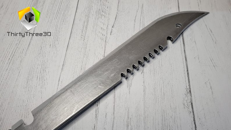 Peut inclure: Un couteau argent&eacute; avec une lame dentel&eacute;e et une pointe pointue. Le couteau est pos&eacute; sur une surface en bois blanc.