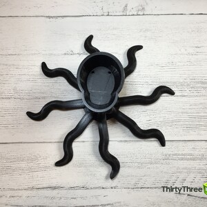 May include: Black octopus-shaped planter with eight tentacles. The planter is made of 3D printed plastic and has a smooth, matte finish.