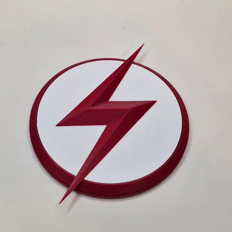 May include: A red lightning bolt emblem on a white circle with a red border. The emblem is a stylized lightning bolt, with sharp angles and a three-dimensional appearance. The design is set against a plain white background.