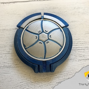 May include: A blue and silver 3D printed circular object with a geometric design. The object is made of multiple pieces that fit together.