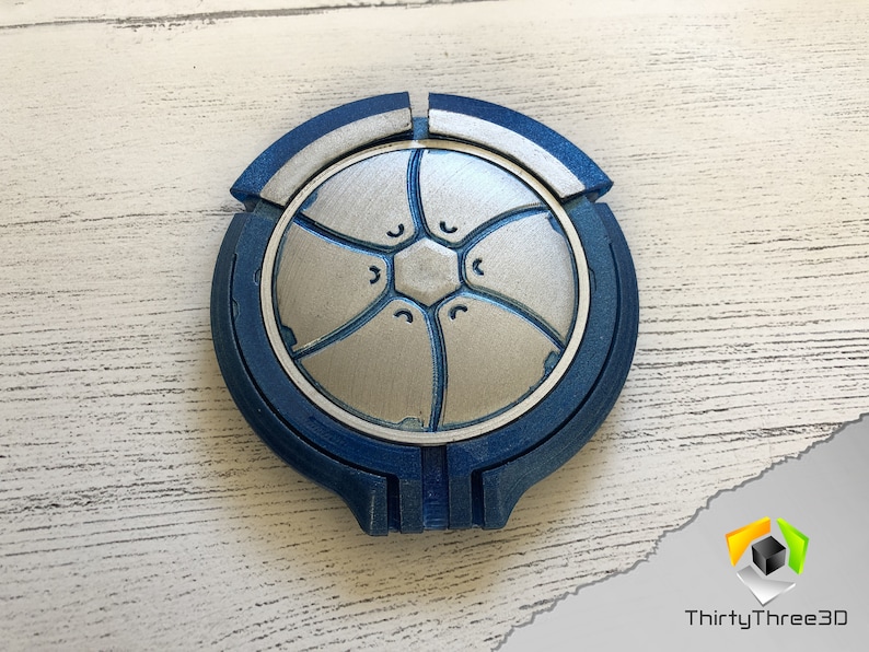 May include: A blue and silver 3D printed circular object with a geometric design. The object is made of multiple pieces that fit together.