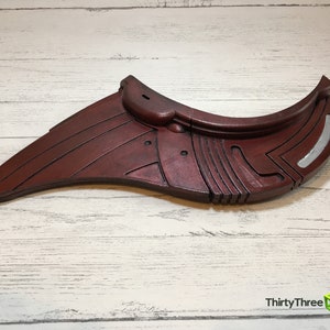 May include: A red and silver 3D printed prop, resembling a futuristic wing or fin. The prop has a detailed, textured surface and a curved shape.
