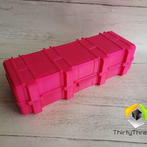 May include: A bright pink plastic storage case with a latch and a textured surface. The case is designed to look like a shipping container.