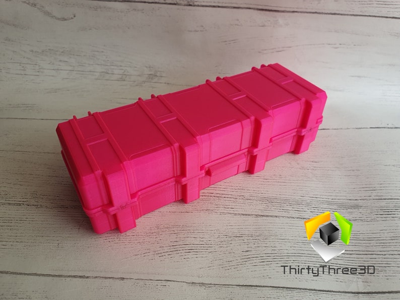 May include: A bright pink plastic storage case with a latch and a textured surface. The case is designed to look like a shipping container.