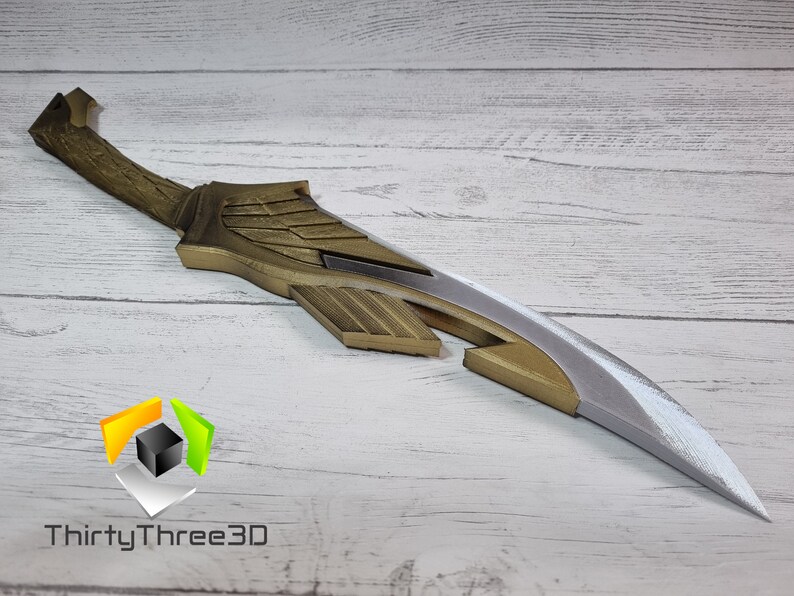May include: A gold and silver decorative sword with a wing design. The sword is made of plastic and is approximately 20 inches long.