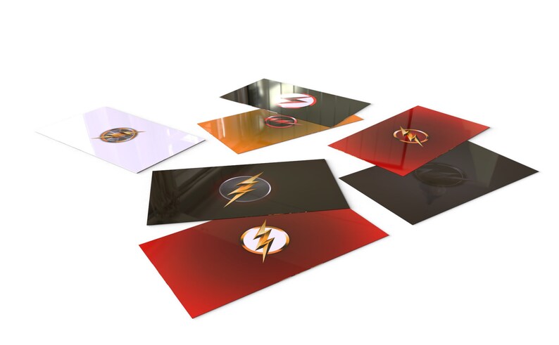 May include: A set of six cards featuring the Flash logo in different colors. The cards are black, white, red, orange, and two shades of gray. Each card has a glossy finish.