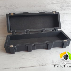 May include: A black plastic storage case with a hinged lid and a latch. The case is empty and has a textured surface.