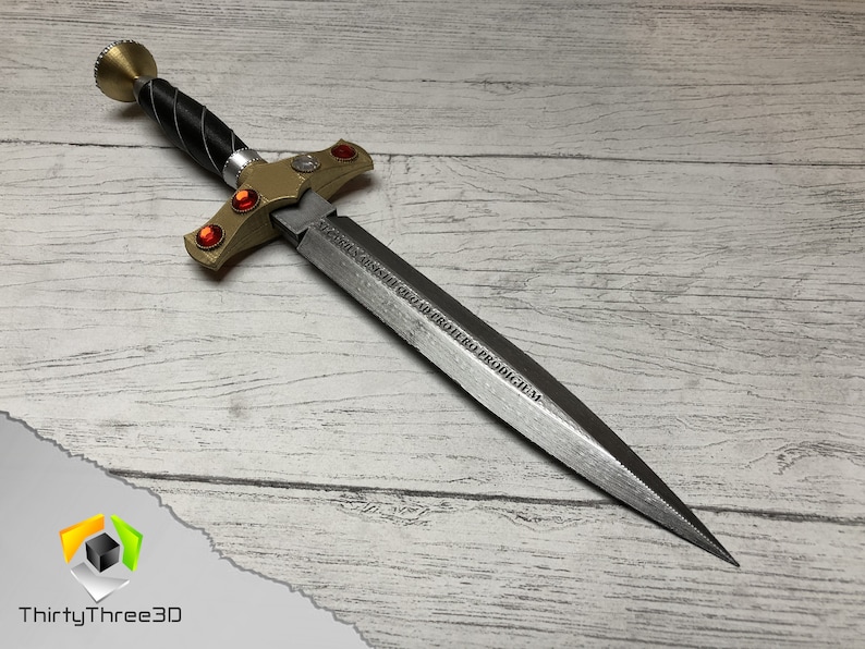 May include: A silver dagger with a gold handle and red gems. The blade is inscribed with the Latin phrase "VICTORIS INSIGNE QUOD PROHERO PRODIGIUM".