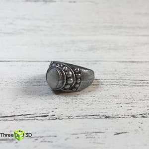 May include: A silver ring with a round, white stone and a decorative band of small, raised circles.