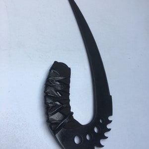 May include: A black, curved, and serrated blade with a black, wrapped handle. The blade is sharp and pointed, and the handle is textured.